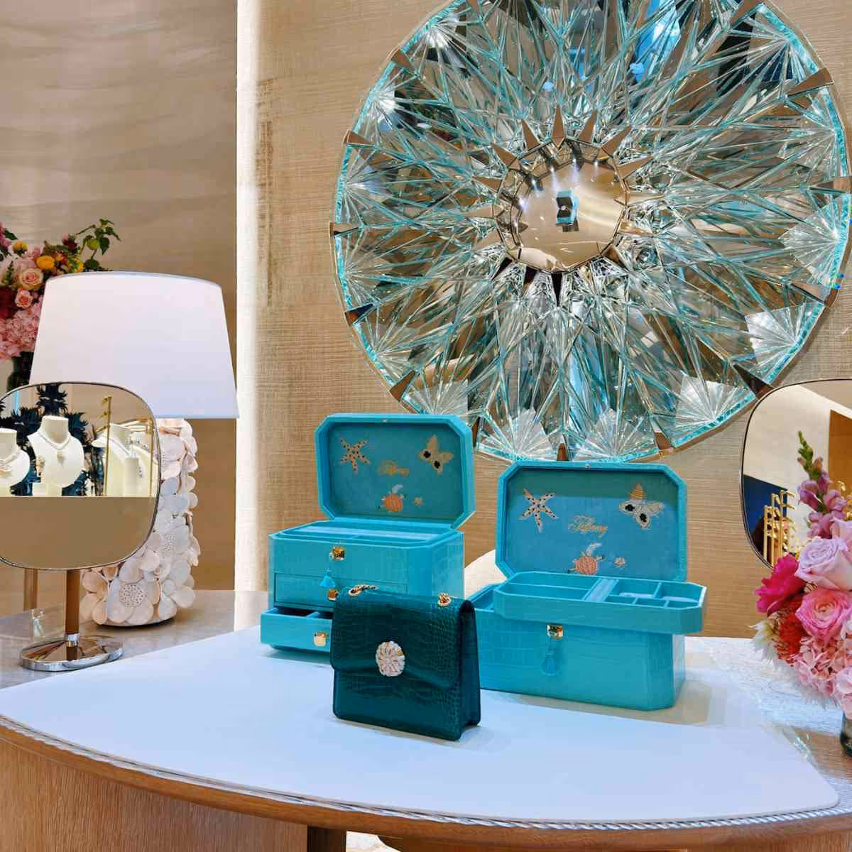 Turquoise jewellery boxes with marine decorations next to a large round mirror