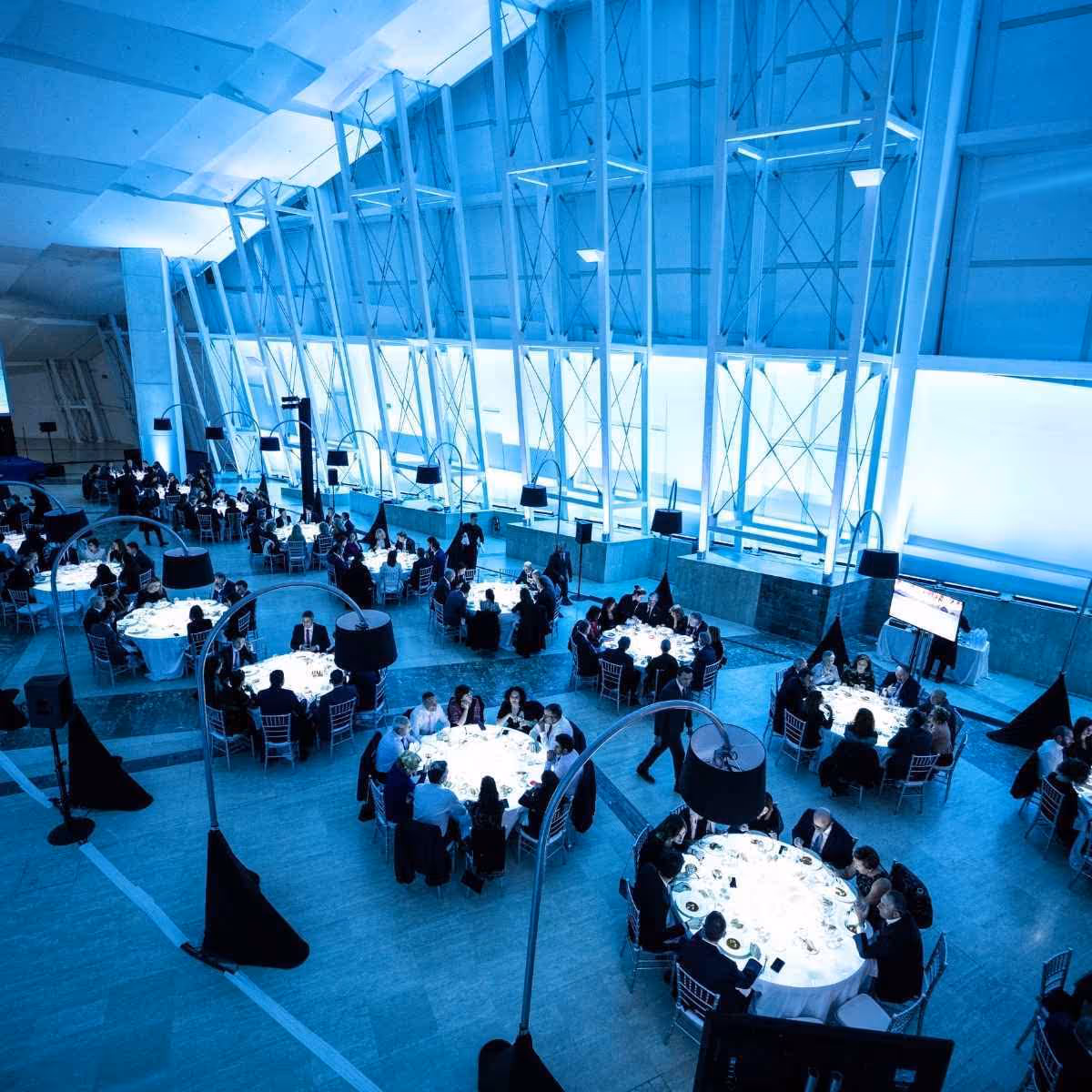 Corporate event with round tables in a modern illuminated blue building