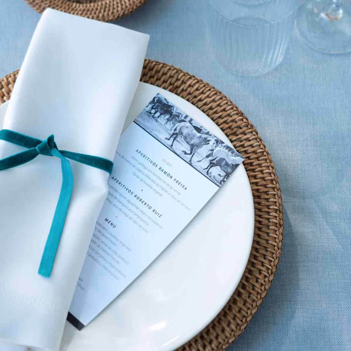 Elegant menu on a white plate with a napkin and an emerald green bow