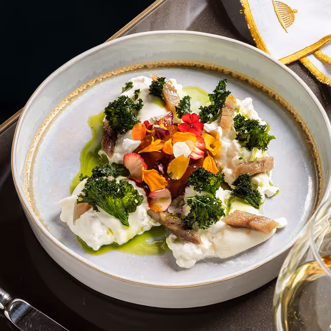 Elegantly presented gourmet dish with broccoli, edible flowers and green sauce