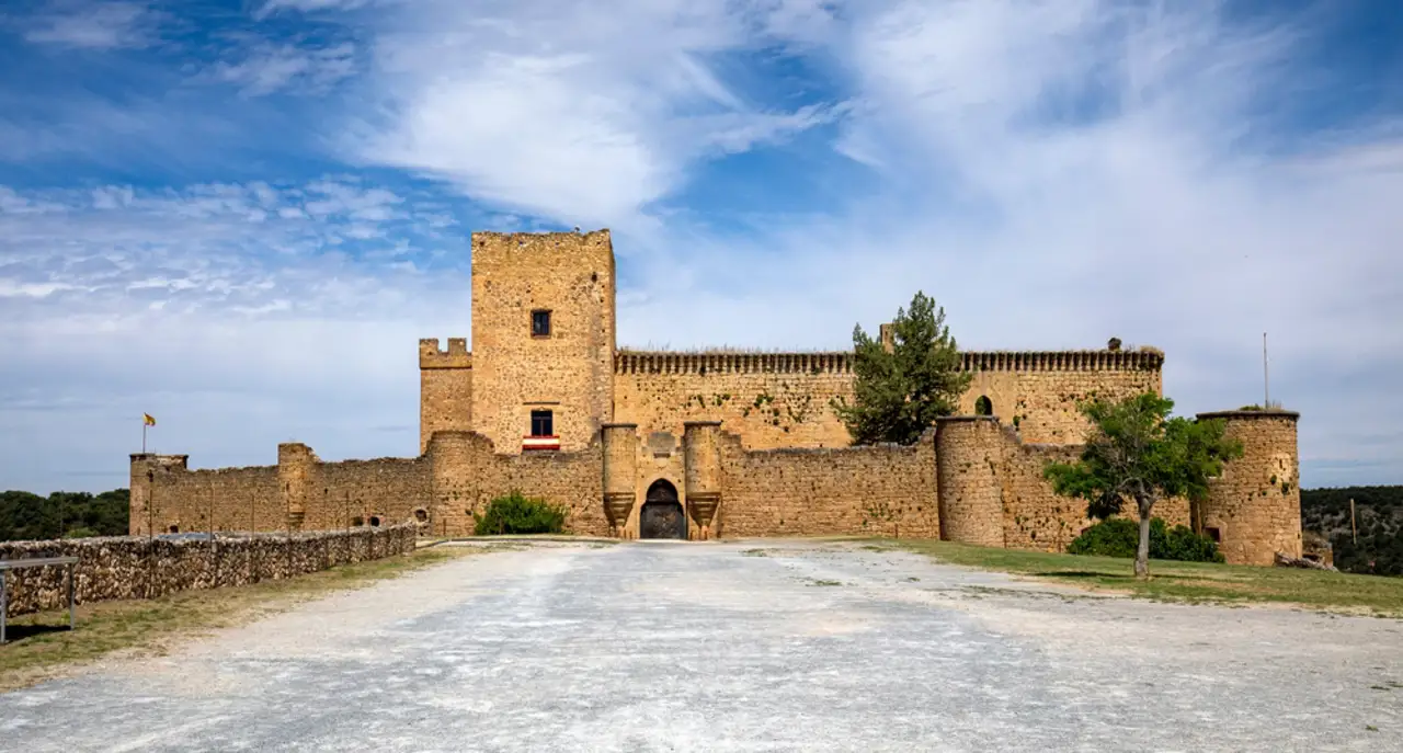 Medieval stone castle with walls under a cloudy blue sky