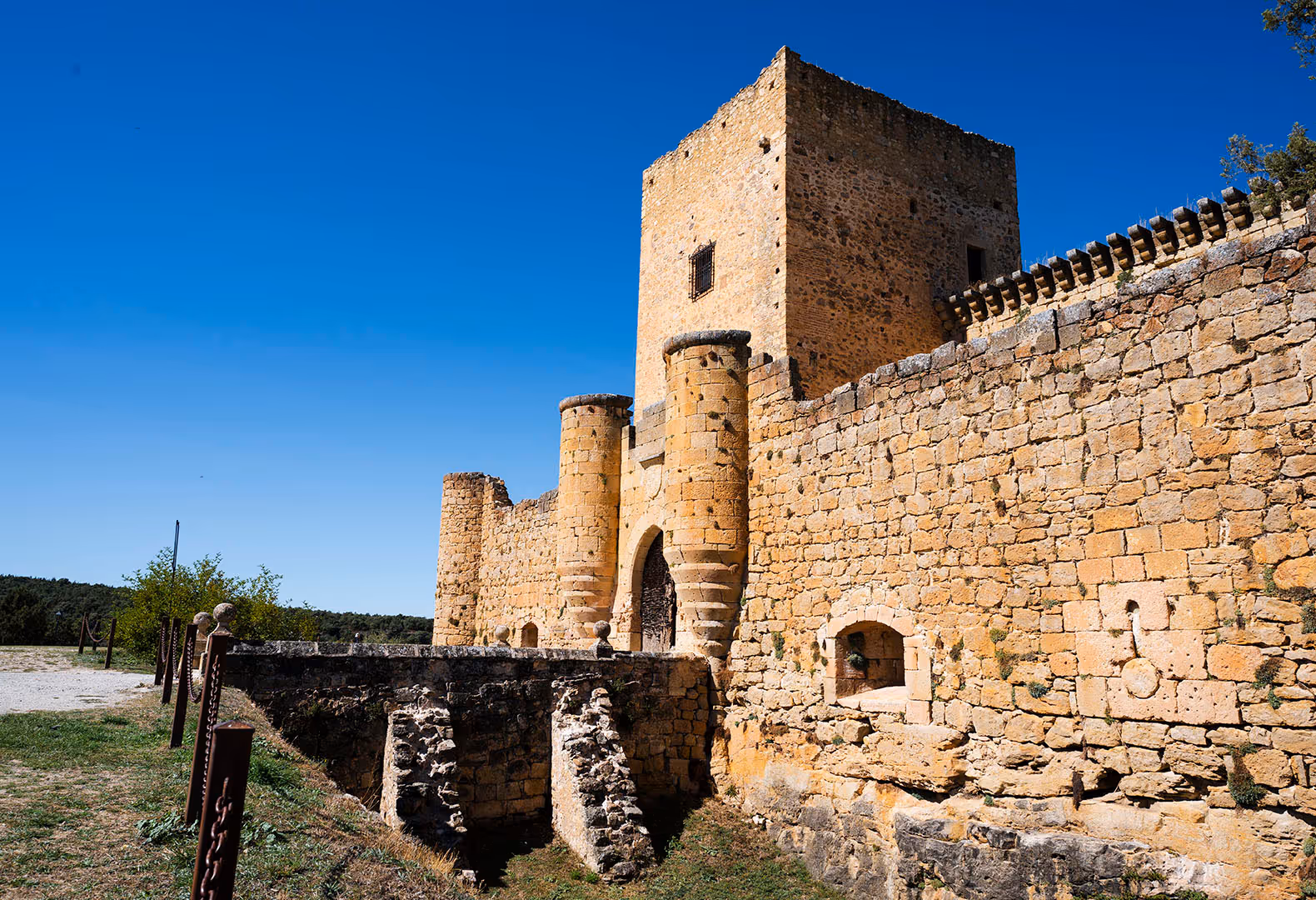 Ancient medieval stone castle with towers and a bridge under a blue sky