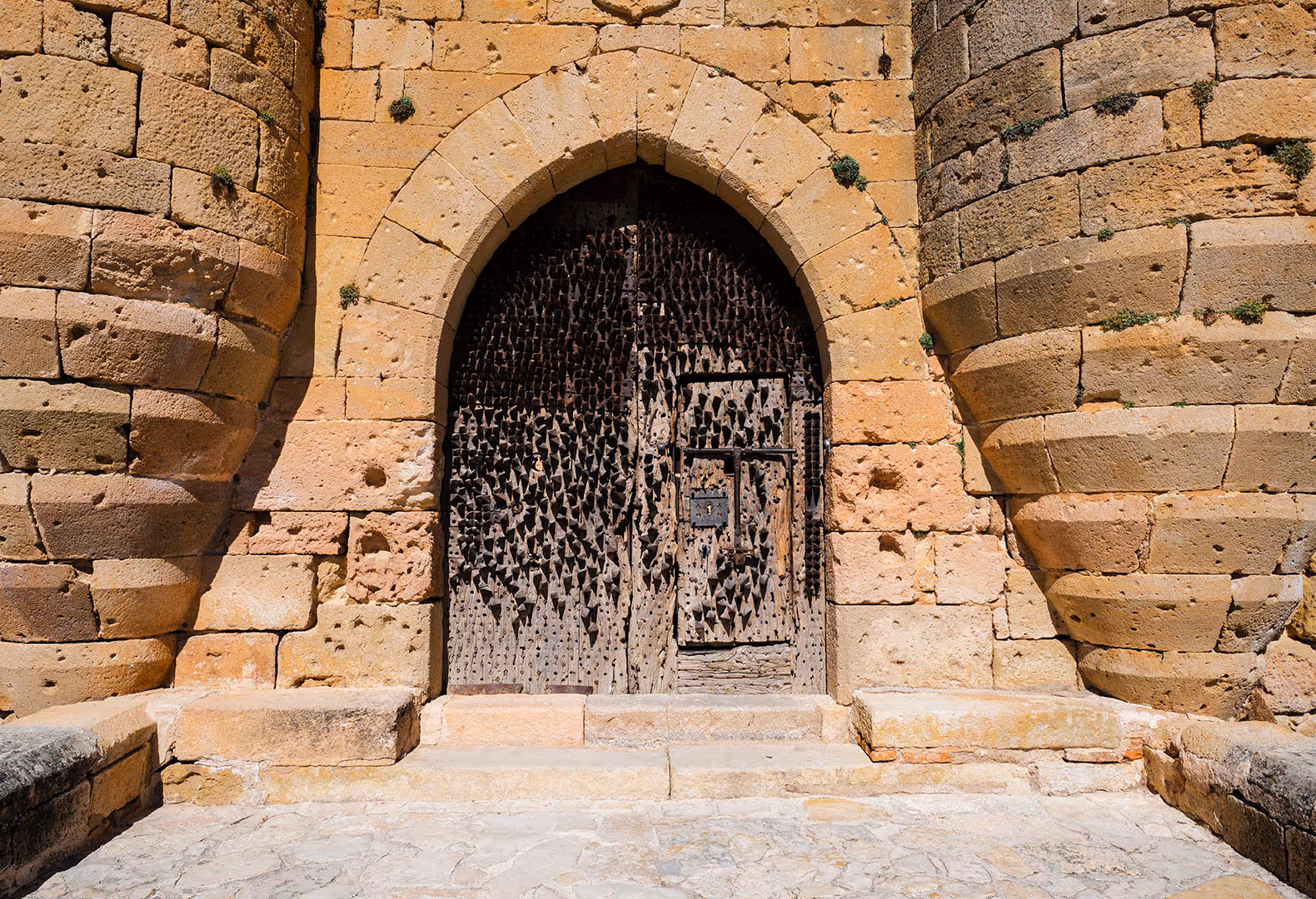 Old stone doorway with a pointed arch and an ornate metal grille