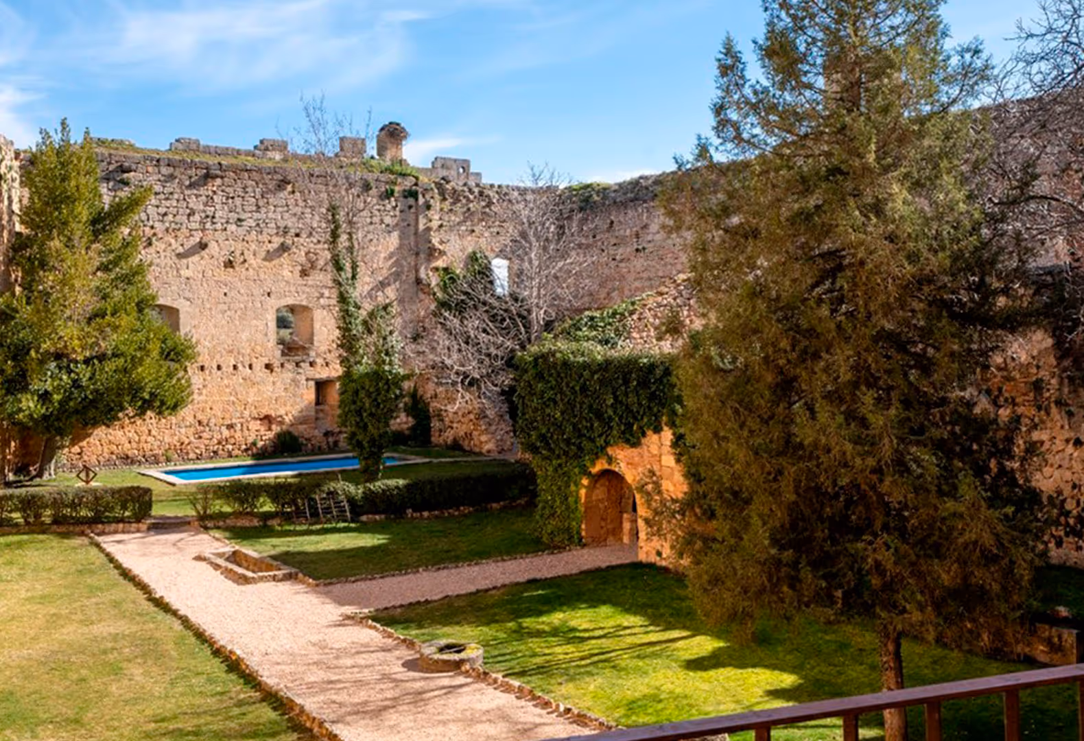 Old castle with a swimming pool and green gardens on a sunny day