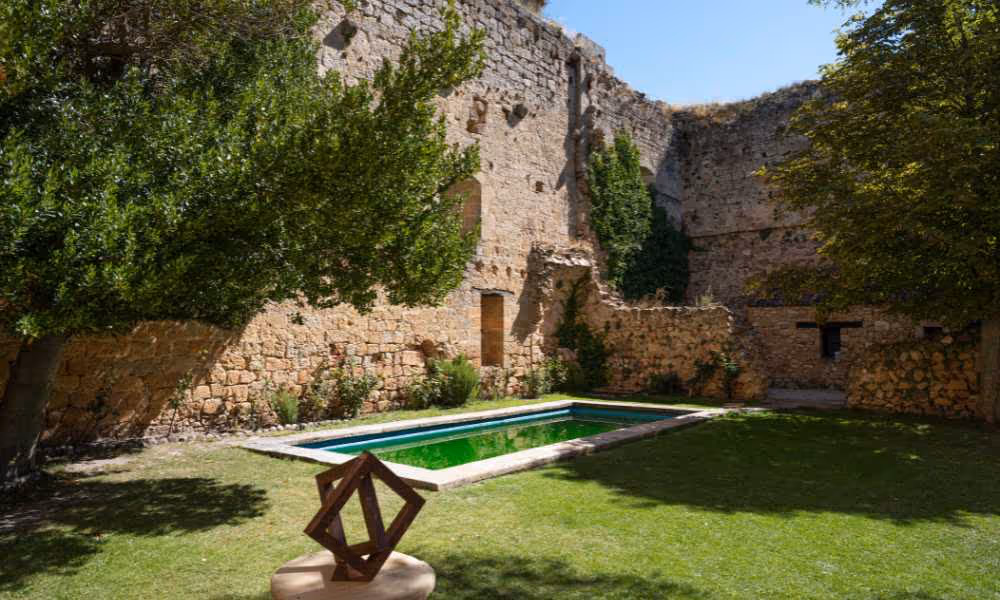 Modern swimming pool in an old castle courtyard with a green garden